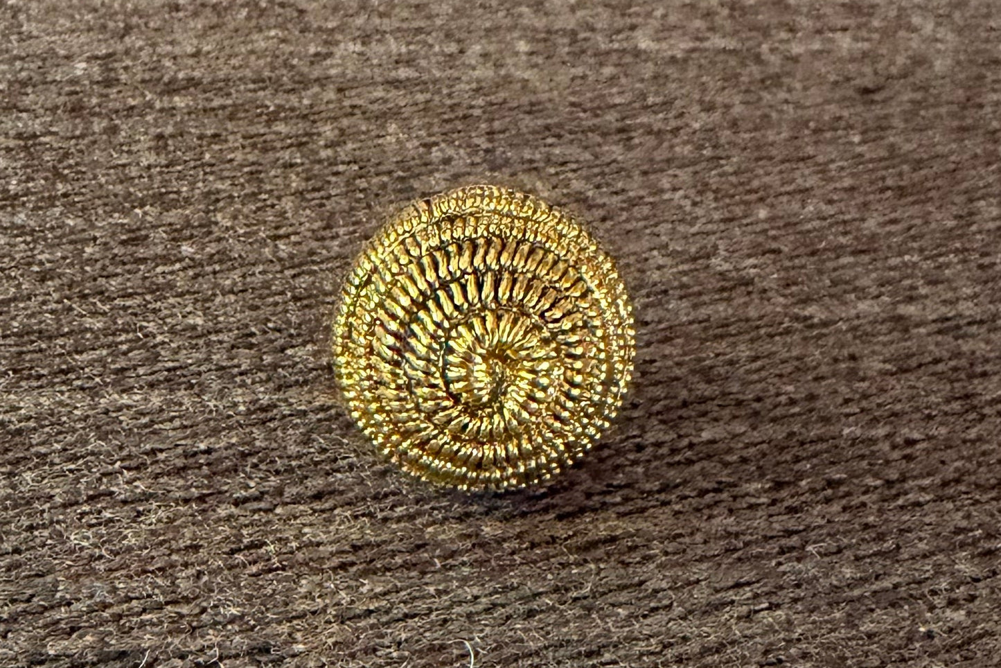 Gold decorative button on a textured surface