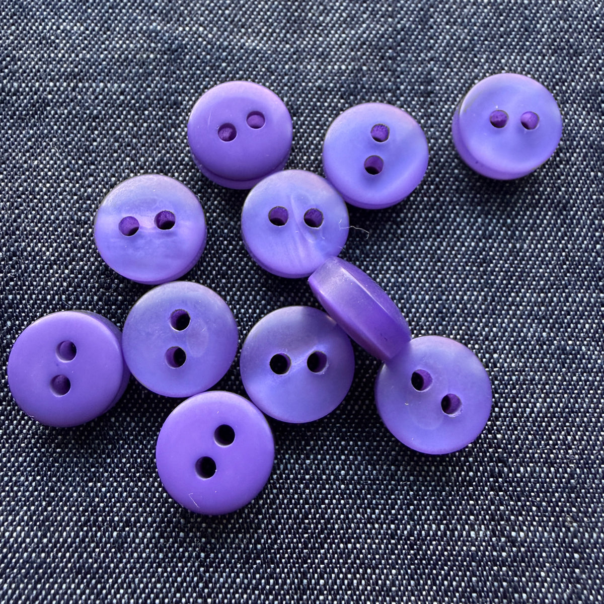 Purple two-hole plastic tablet shirt buttons on denim
