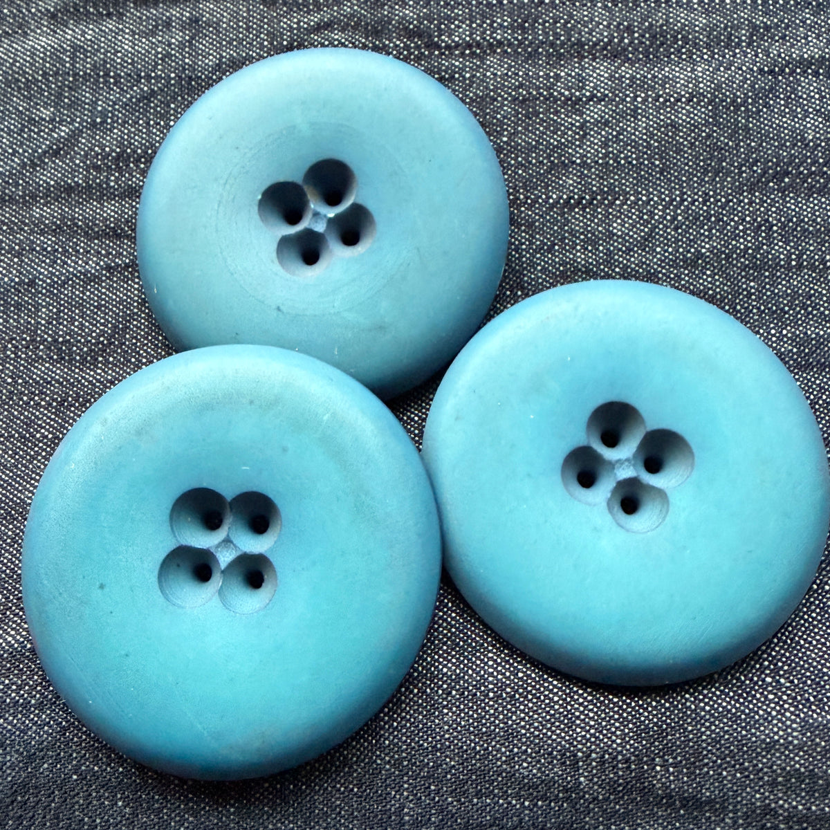 Three blue casein statement buttons on denim.