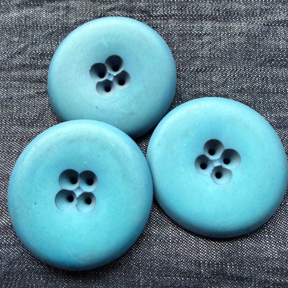 Three blue casein statement buttons on denim.