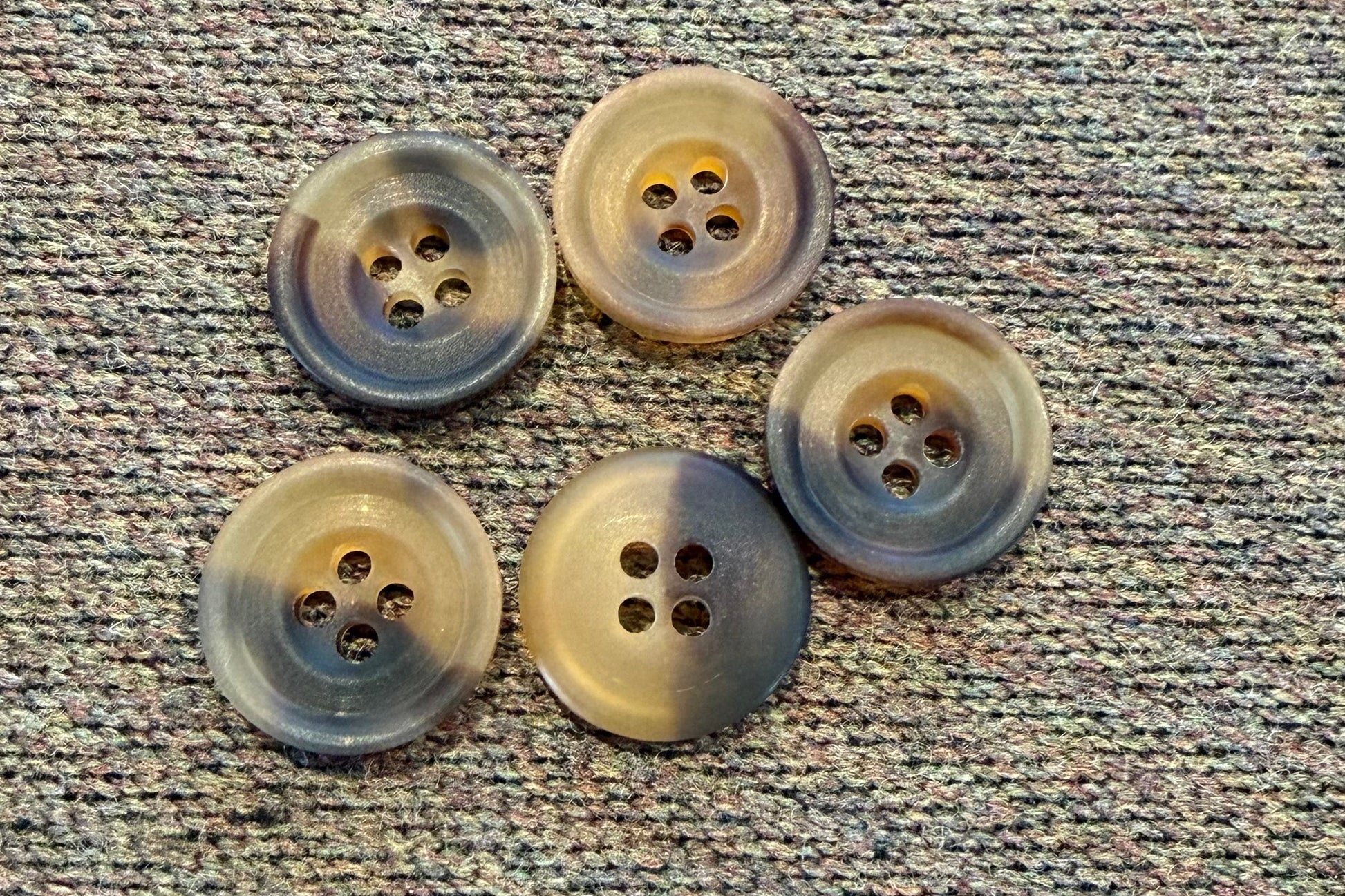 Five brown buttons on a textured fabric background