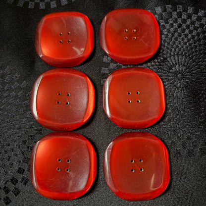 Square red glass buttons with rounded corners catching the light