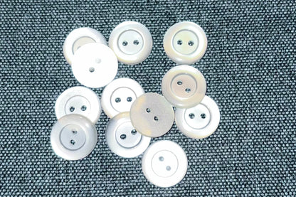 White buttons scattered on a textured gray fabric background