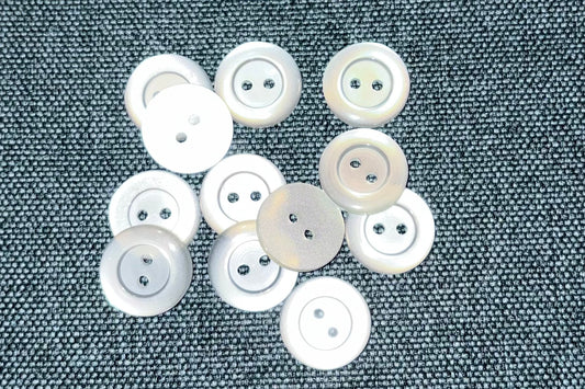 White buttons scattered on a textured gray fabric background