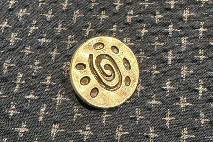 Silver button on a dark fabric with white cross patterns