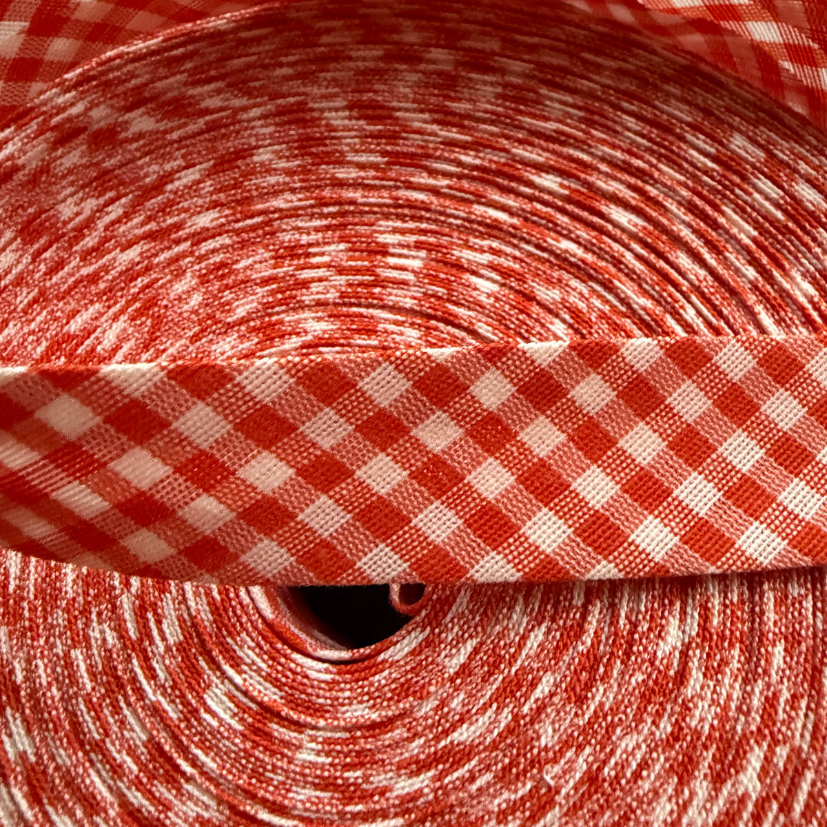Orange and white gingham cotton bias tape on the roll
