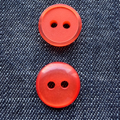 Orange plastic shirt buttons, matte side and glossy side