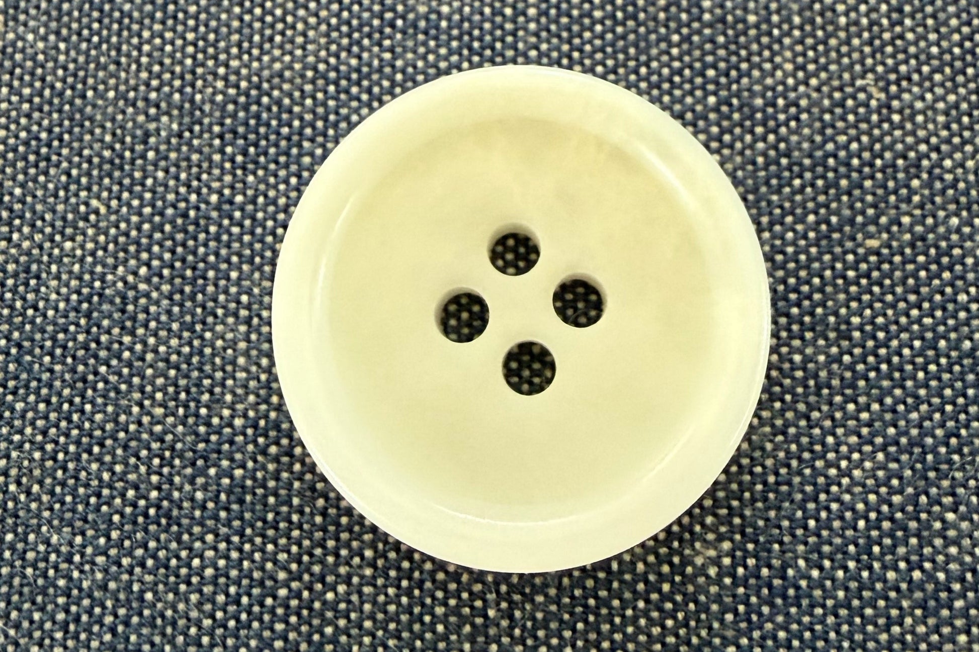 Beige button on a textured gray fabric background