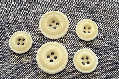Set of five beige buttons on a textured gray fabric background