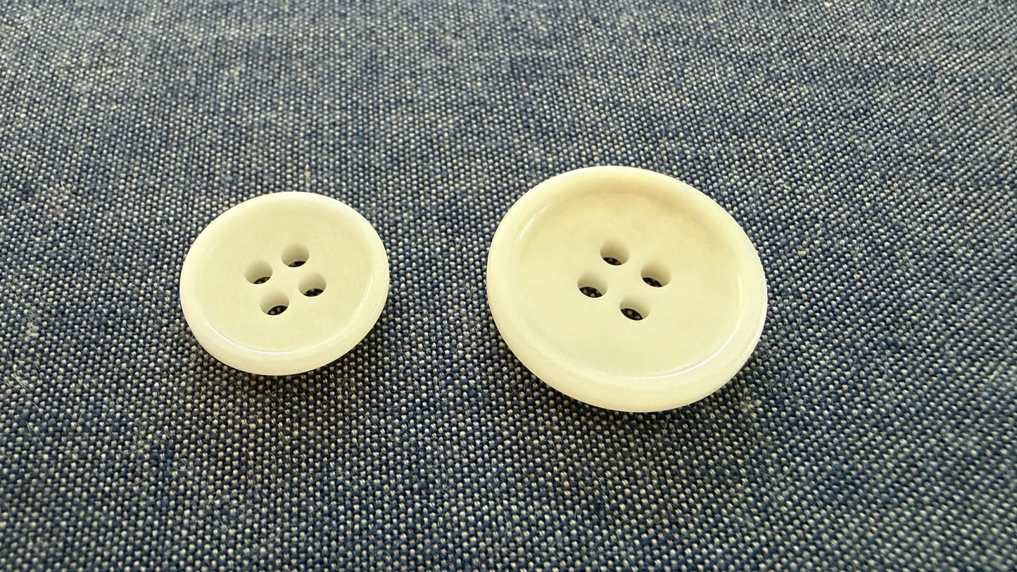 Two beige buttons on a textured gray fabric background