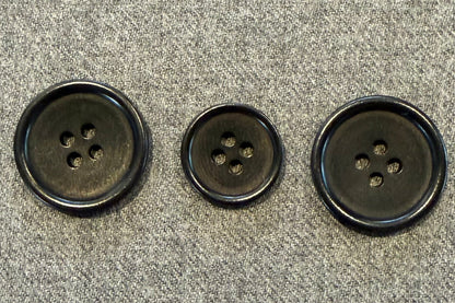 three black buttons on grey fabric