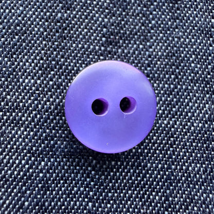 Close-up of thick purple plastic shirt buttons with a pearly swirl