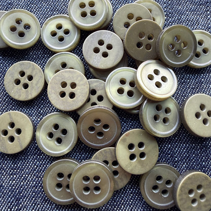 Glossy olive four-hole plastic shirt buttons on denim