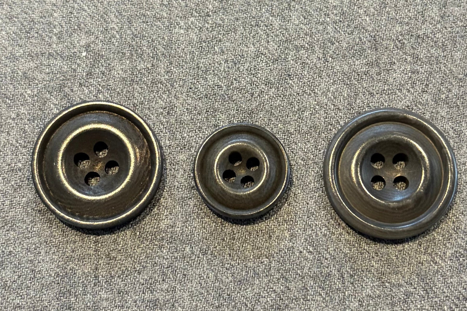 three grey buttons on a textured gray surface