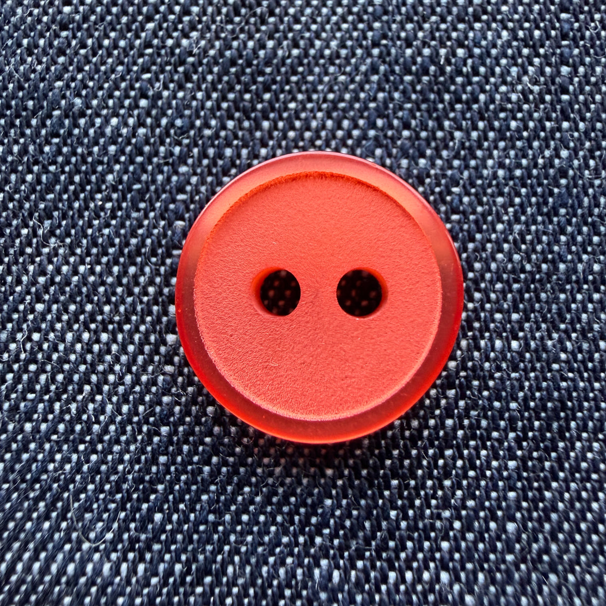 Orange two-hole plastic shirt buttons showing the matte front and glossy back