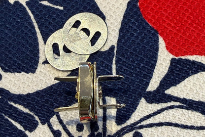 Close-up of a metal snap set on a fabric background with floral pattern