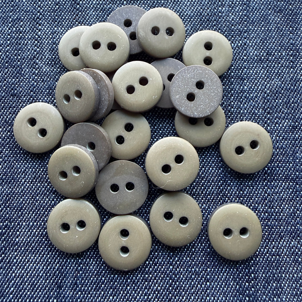 Pile of matte olive two-hole plastic shirt buttons