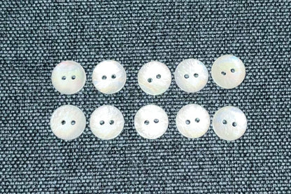 Ten white buttons on a textured fabric surface.