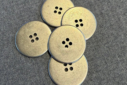Five silver buttons on a textured gray surface
