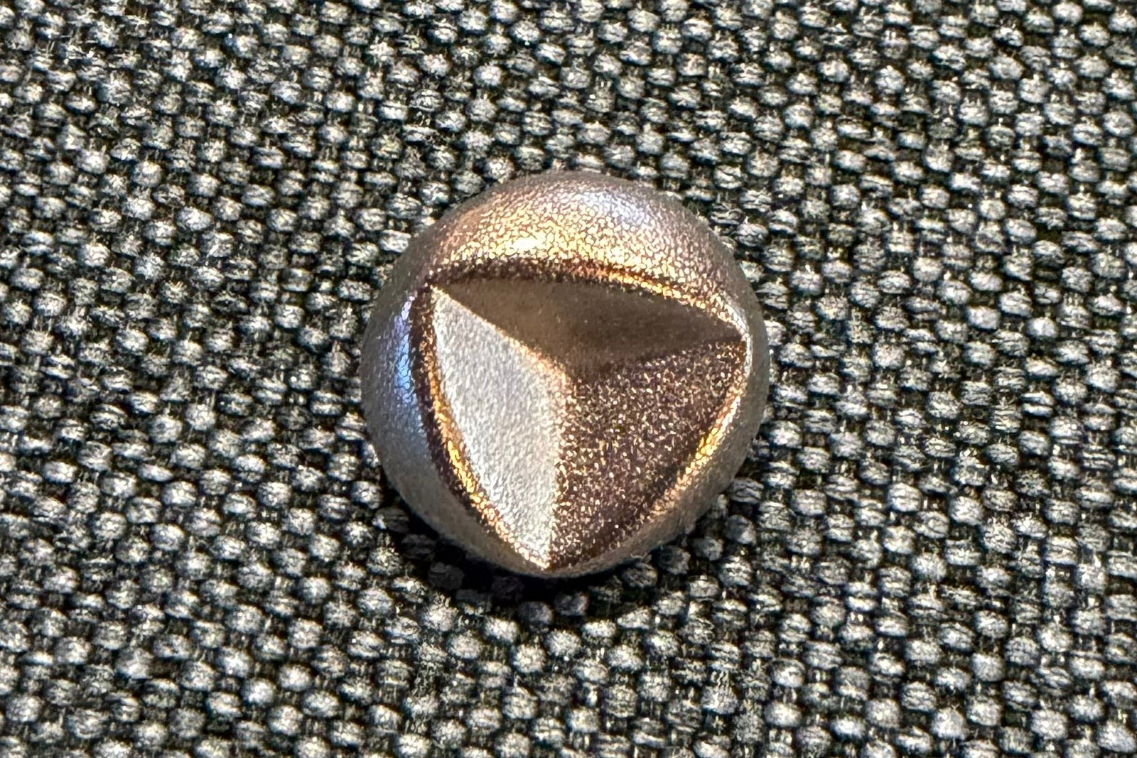 Close-up of a metallic button on gray fabric