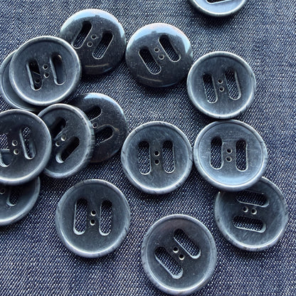 Grey slotted plastic coat buttons scattered on denim