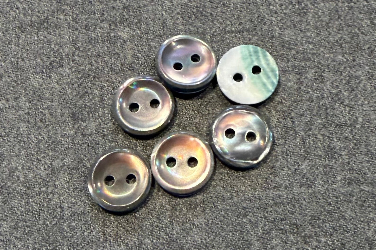 Set of pearly grey buttons on a gray fabric background