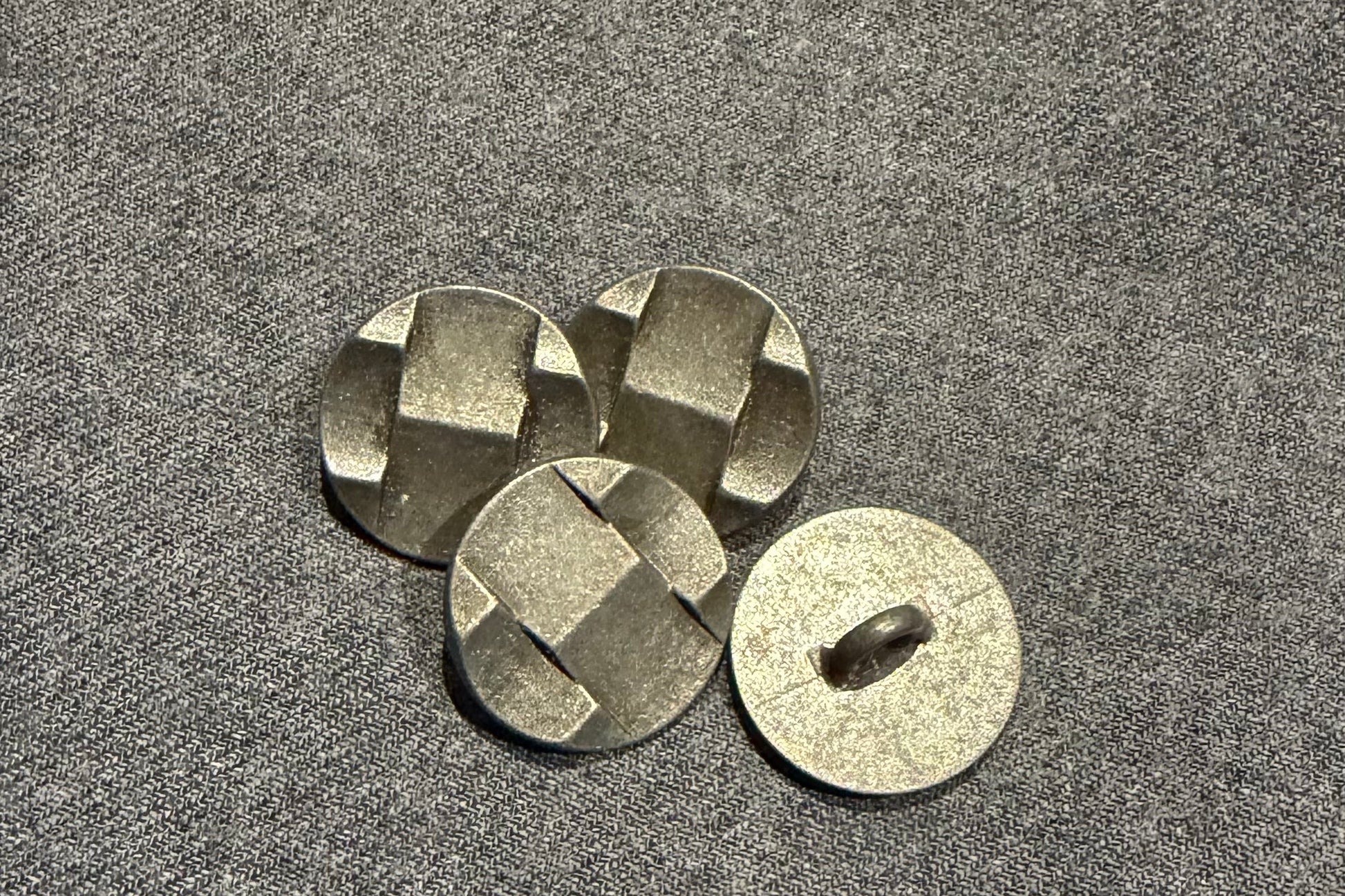 Four metallic buttons on a textured gray surface