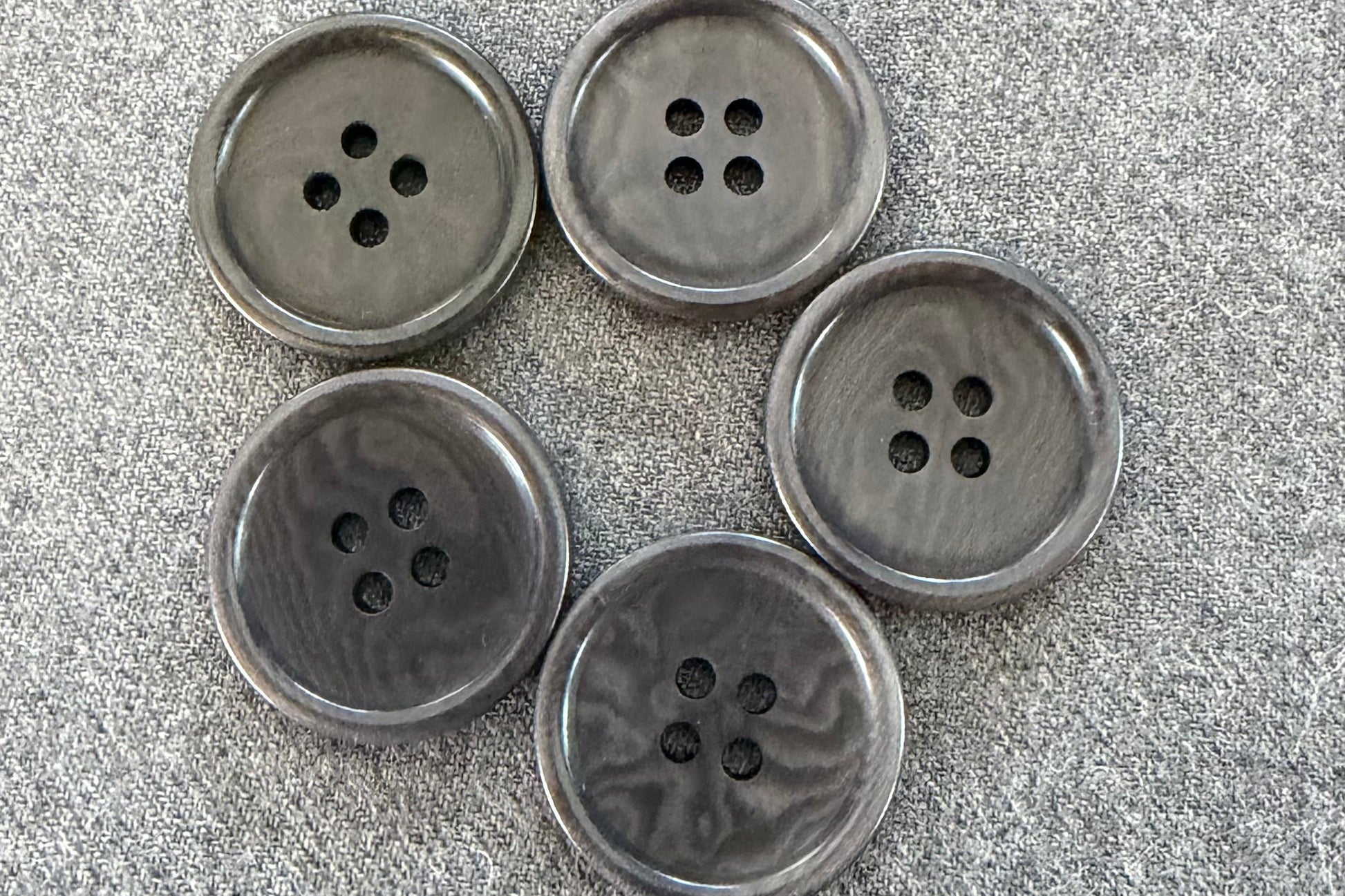 Set of six grey buttons on a textured surface