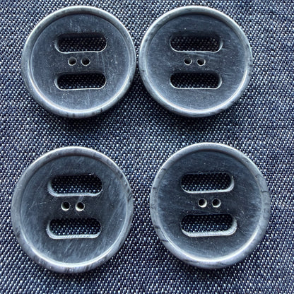 Four grey plastic coat buttons with two wide slots and two small holes