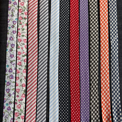 Eleven patterns of cotton bias tape laid side by side: florals, stripes, polka dots and gingham