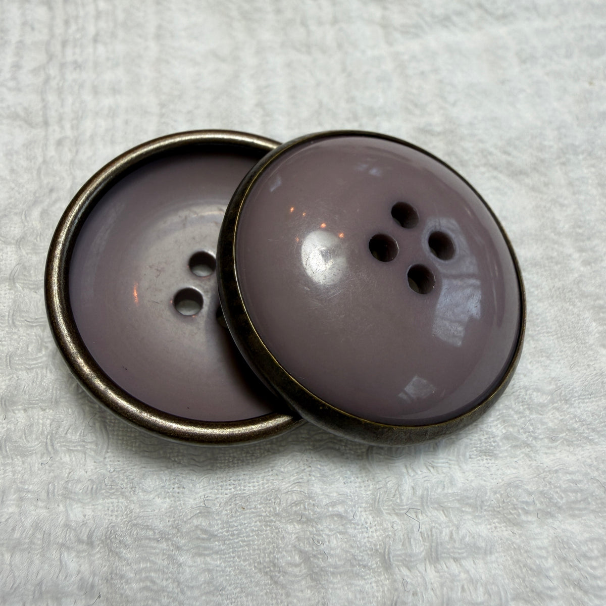 Detail of a mauve concave button with a metal rim.