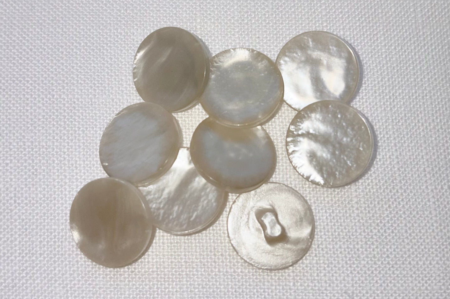 Collection of pearl white buttons on a white fabric background
