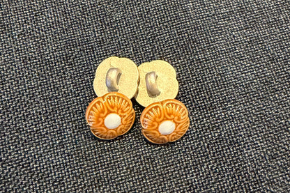 Four floral brown and blue buttons on a blue fabric