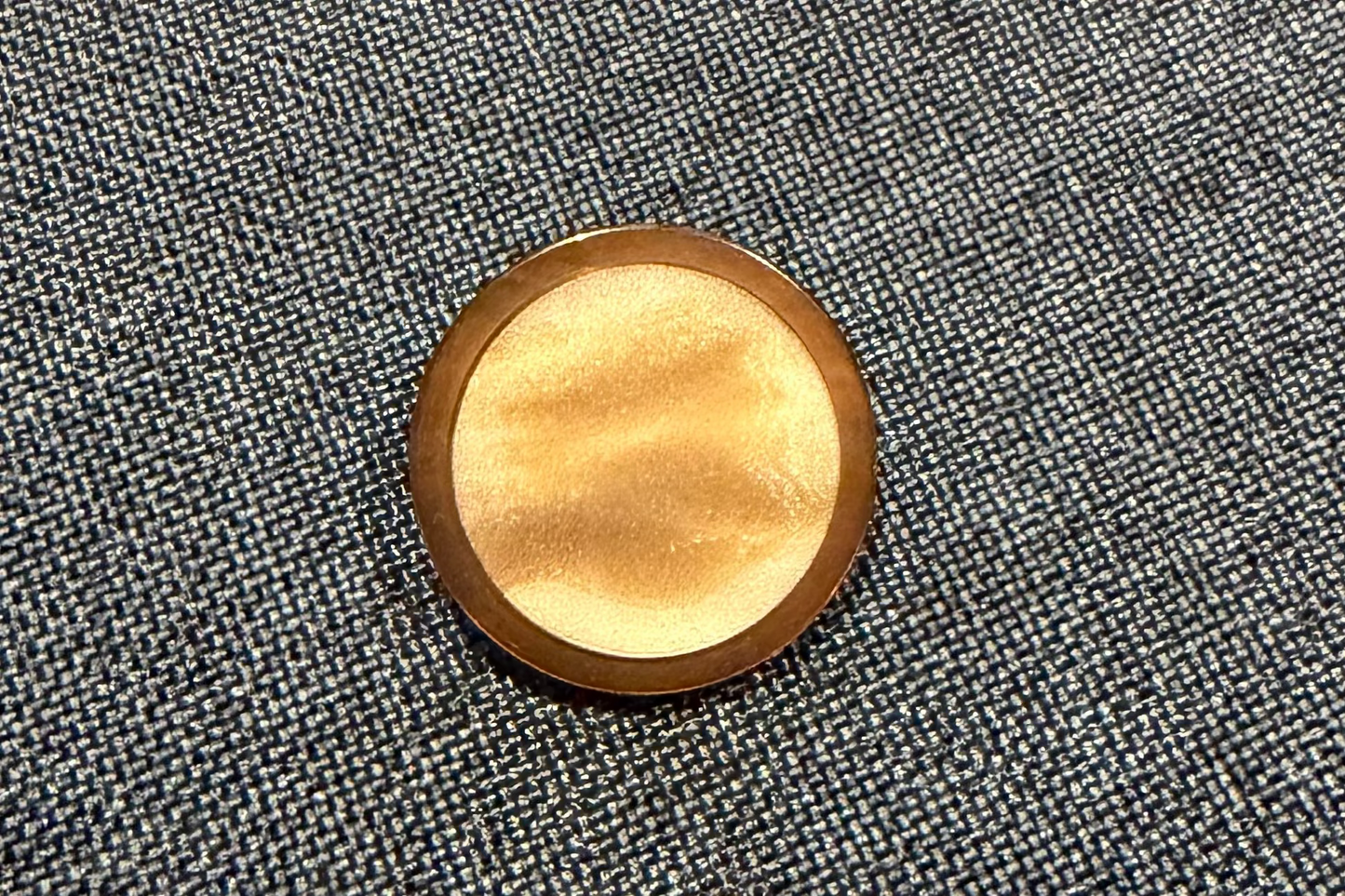 A gold button on a gray fabric background